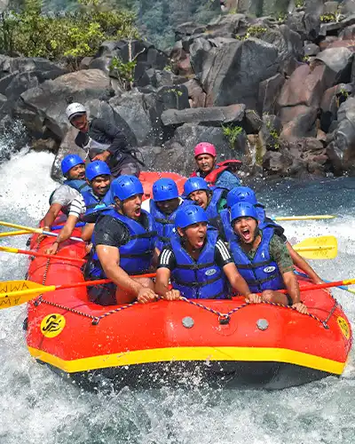 A large group of excited rafters in blue helmets navigating the thrilling rapids on a bright red raft during white water rafting in Dandeli.